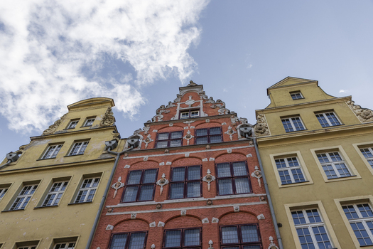 View of historic colorful townhouses with ornate gables and multi pane windows under a blue sky in Gdansk Pomeranian Voivodeship Poland. View of historic colorful townhouses with ornate gables and multi pane windows under a blue sky in Gdansk Pomeranian Voivodeship Poland.