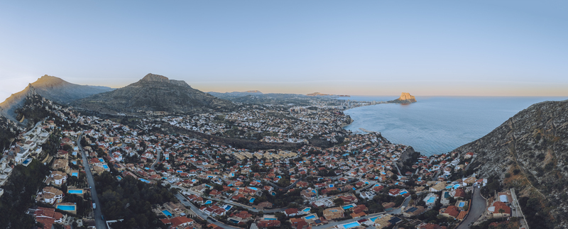 Aerial view of the coastal town of Calp featuring the Penon de Ifach residential areas with red tiled roofs and the Mediterranean coastline at sunset Calp Valencian Community Spain. Aerial view of the coastal town of Calp featuring the Penon de Ifach residential areas with red tiled roofs and the Mediterranean coastline at sunset Calp Valencian Community Spain.