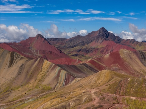 Aerial view of the colorful mineral rich slopes of Rainbow Mountain featuring vibrant red yellow and turquoise stripes under a bright blue sky in the Andes Cusco Cuzco Peru. Aerial view of the colorful mineral rich slopes of Rainbow Mountain featuring vibrant red yellow and turquoise stripes under a bright blue sky in the Andes Cusco Cuzco Peru.