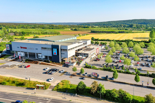 Bamberg Germany 02 May 2026 Aerial view of Brose Arena with its modern facade large parking area and surrounding green landscapes under a clear sky.