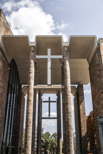 View of the modern entrance and stone columns of Coventry Cathedral with two crosses against a blue sky in Coventry England United Kingdom.