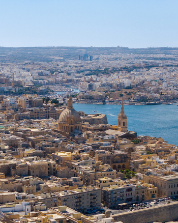 Aerial view of the Basilica of Our Lady of Mount Carmel surrounded by historic limestone buildings and the harbor in Valletta Port Region Malta. Aerial view of the Basilica of Our Lady of Mount Carmel surrounded by historic limestone buildings and the harbor in Valletta Port Region Malta.