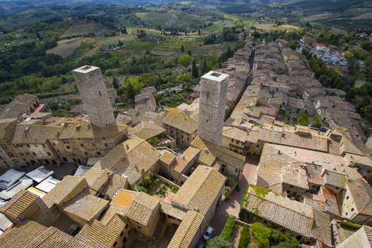 View of terracotta rooftops and medieval towers punctuate the skyline against a backdrop of rolling green hills bathed in the warm Italian sun San Gimignano Tuscany Italy. View of terracotta rooftops and medieval towers punctuate the skyline against a backdrop of rolling green hills bathed in the warm Italian sun San Gimignano Tuscany Italy.