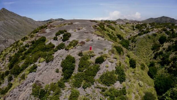 Aerial view of a woman in a red dress on a volcanic ridge near Bromo Indonesia. Aerial view of a woman in a red dress on a volcanic ridge near Bromo Indonesia.