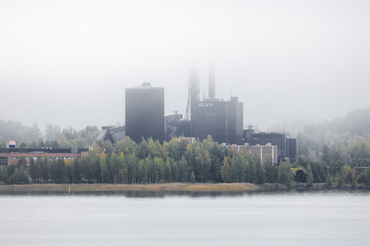 View of the Alva power plant partially obscured by fog with surrounding trees and a lake in the foreground in Jyvaskyla Central Finland Finland.