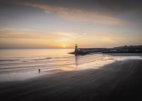 Aerial view of Balbriggan Harbour at sunset with calm sea sandy beach and soft golden light in Balbriggan County Dublin Ireland. Aerial view of Balbriggan Harbour at sunset with calm sea sandy beach and soft golden light in Balbriggan County Dublin Ireland.