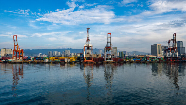 View of Cebu Port Authority with shipping containers large cranes and calm water under a blue sky in Cebu City Central Visayas Philippines. View of Cebu Port Authority with shipping containers large cranes and calm water under a blue sky in Cebu City Central Visayas Philippines.