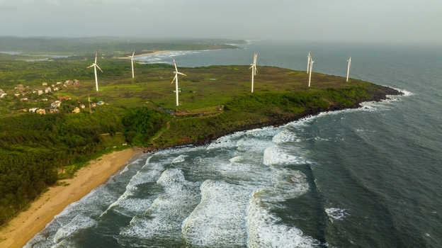Aerial view of Devgad Windmills situated on a green coastal headland with crashing waves along the sandy beach in Devgad Maharashtra India. Aerial view of Devgad Windmills situated on a green coastal headland with crashing waves along the sandy beach in Devgad Maharashtra India.