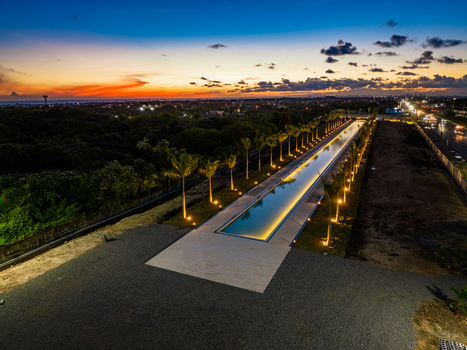 Aerial view of the Casa Arquidiocesana Maria de La Altagracia with a long illuminated pool lined with palm trees at sunset in Santo Domingo Este Santo Domingo Province Dominican Republic. Aerial view of the Casa Arquidiocesana Maria de La Altagracia with a long illuminated pool lined with palm trees at sunset in Santo Domingo Este Santo Domingo Province Dominican Republic.