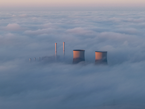 Aerial view of RWE Clauscentrale power plant with cooling towers and chimneys emerging from a thick layer of fog under a soft morning light Maasbracht Limburg Netherlands. Aerial view of RWE Clauscentrale power plant with cooling towers and chimneys emerging from a thick layer of fog under a soft morning light Maasbracht Limburg Netherlands.