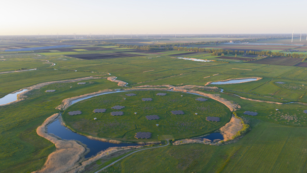 Aerial view of the LOFAR superterp radio telescope station on a circular island surrounded by green fields and water channels at sunset in Buinen Drenthe Netherlands. Aerial view of the LOFAR superterp radio telescope station on a circular island surrounded by green fields and water channels at sunset in Buinen Drenthe Netherlands.