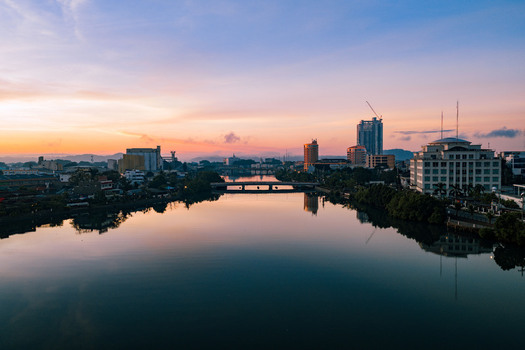 Aerial view of the tranquil river reflecting the vibrant sunset hues behind the cityscape and bridge Iloilo City Philippines. Aerial view of the tranquil river reflecting the vibrant sunset hues behind the cityscape and bridge Iloilo City Philippines.