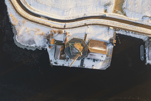 Aerial view of Zaanse Schans windmill surrounded by snow covered landscape and frozen water in Zaandam Noord Holland Netherlands. Aerial view of Zaanse Schans windmill surrounded by snow covered landscape and frozen water in Zaandam Noord Holland Netherlands.