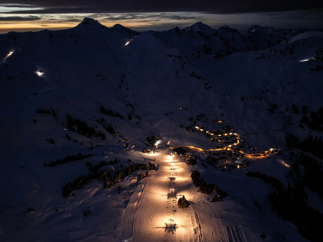 Aerial view of Les Crosets ski resort with illuminated ski slopes and village lights nestled among snow covered mountain peaks at night in Val d Illiez Valais Switzerland. Aerial view of Les Crosets ski resort with illuminated ski slopes and village lights nestled among snow covered mountain peaks at night in Val d Illiez Valais Switzerland.