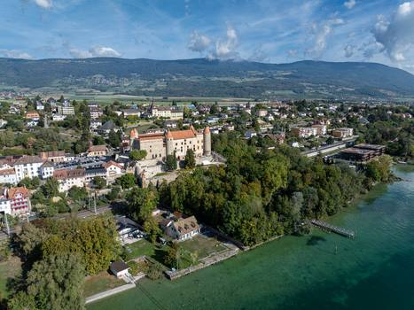 Aerial view of the historic Chateau de Grandson surrounded by lush trees and the town of Grandson along the lake Grandson Vaud Switzerland.
