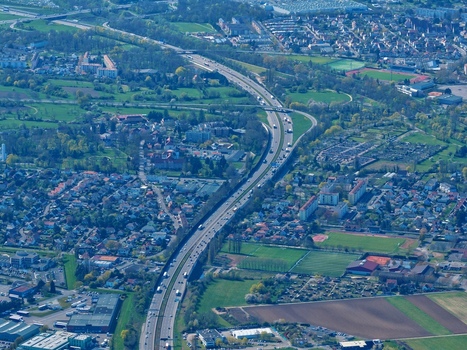 Aerial view of a sinuous highway cutting through verdant fields and quaint cityscapes a pathway for vehicles under the vast sky Sausheim Grand Est France.