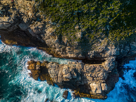 Aerial view of rugged granite cliffs and deep blue ocean waves crashing against the rocky coastline of Torndirrup Western Australia Australia. Aerial view of rugged granite cliffs and deep blue ocean waves crashing against the rocky coastline of Torndirrup Western Australia Australia.