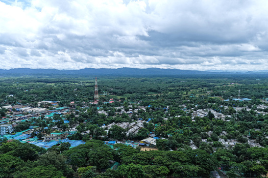 Aerial view of Camp 7 Kutupalang Expansion Sites with dense shelters blue tarpaulin roofs lush trees and a communication tower in Cox s Bazar District Chittagong Division Bangladesh.