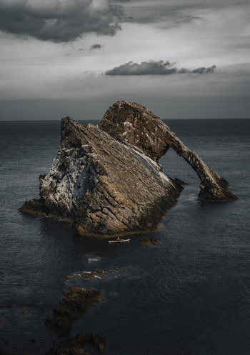 View of dramatic rock arch over the sea with a cloudy sky Portknockie Great Britain.
