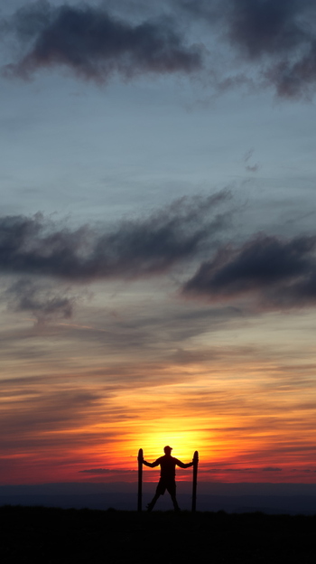 View of the silhouette of a person standing at Colomby de Gex against a vibrant sunset with orange and red clouds in Echenevex Auvergne Rhone Alpes France. View of the silhouette of a person standing at Colomby de Gex against a vibrant sunset with orange and red clouds in Echenevex Auvergne Rhone Alpes France.