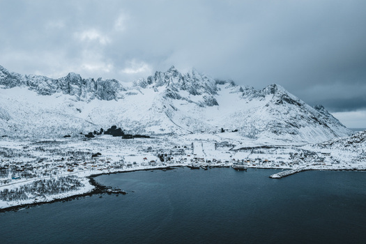 Aerial view of a serene fjord embracing a snow laden village nestled beneath majestic frosted mountains Mefjordvær Troms Norway. Aerial view of a serene fjord embracing a snow laden village nestled beneath majestic frosted mountains Mefjordvær Troms Norway.