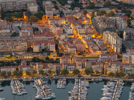 Aerial view of the marina with numerous boats docked in the harbor alongside the illuminated historic buildings and urban architecture of Antibes Provence Alpes Cote d Azur France. Aerial view of the marina with numerous boats docked in the harbor alongside the illuminated historic buildings and urban architecture of Antibes Provence Alpes Cote d Azur France.
