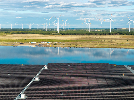Aerial view of the floating solar farm on Cottbuser Ostsee with wind turbines in the background under a blue sky in Cottbus Brandenburg Germany. Aerial view of the floating solar farm on Cottbuser Ostsee with wind turbines in the background under a blue sky in Cottbus Brandenburg Germany.