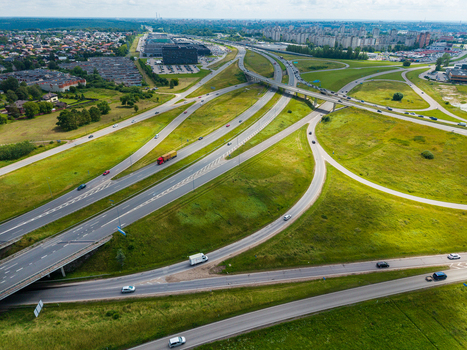 Aerial view of a highway interchange with multi level roads green grassy embankments and vehicles in Kaunas Kaunas County Lithuania.