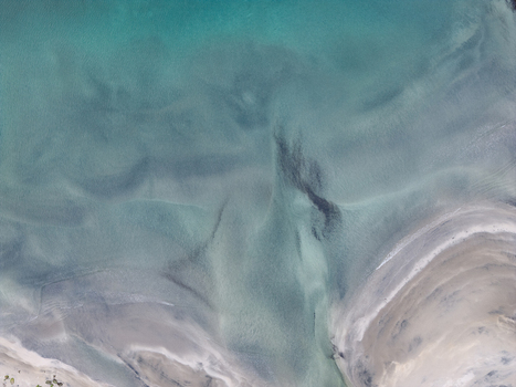 Aerial view of the turquoise waters and intricate sand patterns along the coastline of Senja Troms Norway.