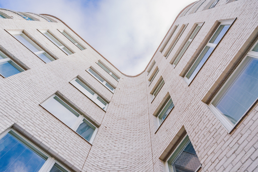 View of a modern white brick building with a curved facade and many windows under a cloudy sky in Helsinki Uusimaa Finland.