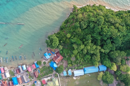 Aerial view of Pulau Maginti featuring a coastal village with colorful rooftops small boats moored along the shoreline and lush green vegetation in Maginti South East Sulawesi Indonesia.
