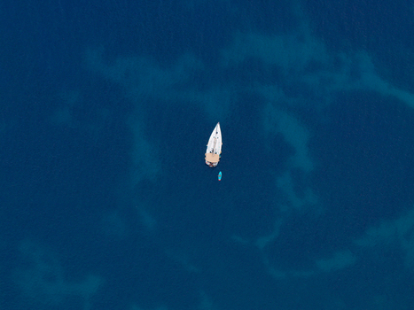Aerial view of a sailboat and a small boat floating in the deep blue waters of the Riserva Naturale Orientata dello Zingaro San Vito Lo Capo Sicilia Italy. Aerial view of a sailboat and a small boat floating in the deep blue waters of the Riserva Naturale Orientata dello Zingaro San Vito Lo Capo Sicilia Italy.