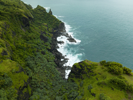 Aerial view of rugged cliffs cloaked in verdant vegetation meeting the turquoise sea in a dramatic coastal embrace at Pengilon Hill Gunungkidul Regency Daerah Istimewa Yogyakarta Indonesia. Aerial view of rugged cliffs cloaked in verdant vegetation meeting the turquoise sea in a dramatic coastal embrace at Pengilon Hill Gunungkidul Regency Daerah Istimewa Yogyakarta Indonesia.