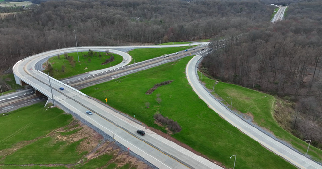 Aerial view of a highway interchange with looping ramps and surrounding green grassy fields and dense forest in Manheim Pennsylvania United States. Aerial view of a highway interchange with looping ramps and surrounding green grassy fields and dense forest in Manheim Pennsylvania United States.