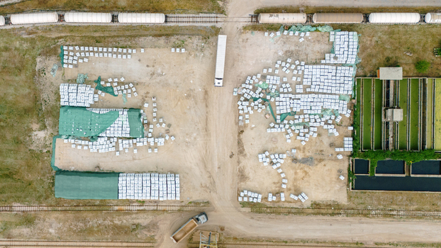 Aerial view of industrial storage yard with stacks of white bags green tarps a parked truck and railway tracks with tanker cars in Sabac Vojvodina Serbia. Aerial view of industrial storage yard with stacks of white bags green tarps a parked truck and railway tracks with tanker cars in Sabac Vojvodina Serbia.