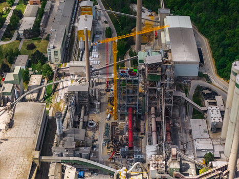 Aerial view of the industrial complex of a cement factory featuring tall chimneys silos and a yellow construction crane Mokra Horakov Jihomoravsky kraj Czechia. Aerial view of the industrial complex of a cement factory featuring tall chimneys silos and a yellow construction crane Mokra Horakov Jihomoravsky kraj Czechia.