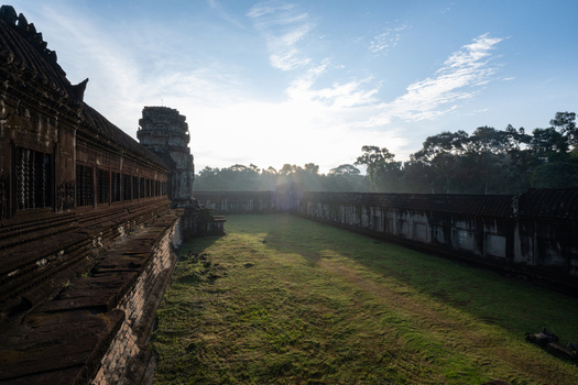 View of the ancient stone walls and grassy courtyard of Angkor Wat at sunrise in Krong Siem Reap Siem Reap Province Cambodia. View of the ancient stone walls and grassy courtyard of Angkor Wat at sunrise in Krong Siem Reap Siem Reap Province Cambodia.