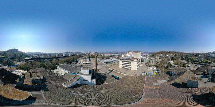Aerial view of an industrial complex with a tall brick chimney rooftops and a railway viaduct under a clear blue sky in Lenzburg Aargau Switzerland. Aerial view of an industrial complex with a tall brick chimney rooftops and a railway viaduct under a clear blue sky in Lenzburg Aargau Switzerland.