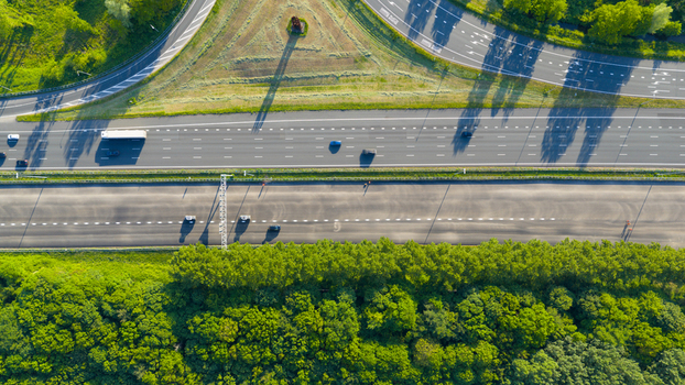 Waardenburg Netherlands 09 May 2026 Aerial view of a multi lane highway with cars and a truck driving past lush green trees and an interchange. Waardenburg Netherlands 09 May 2026 Aerial view of a multi lane highway with cars and a truck driving past lush green trees and an interchange.