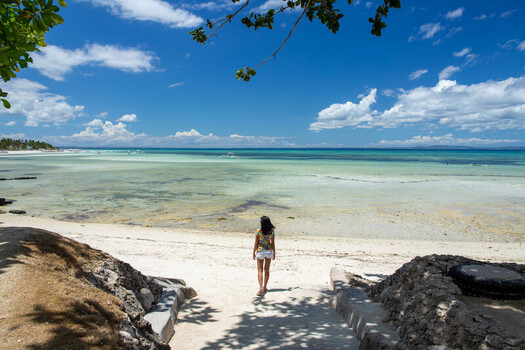 Cebu Central Visayas Philippines 21 June 2026 View of a woman walking on the white sand beach of Bantayan Island towards the turquoise sea under a clear blue sky. Cebu Central Visayas Philippines 21 June 2026 View of a woman walking on the white sand beach of Bantayan Island towards the turquoise sea under a clear blue sky.