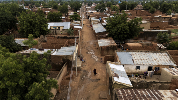 Aerial view of the town of Dambatta with its traditional mud houses corrugated metal roofs and a central dirt road lined with trees in Dambatta Kano Nigeria. Aerial view of the town of Dambatta with its traditional mud houses corrugated metal roofs and a central dirt road lined with trees in Dambatta Kano Nigeria.