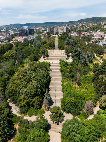 Aerial view of the Monument of the Bulgarian Soviet Friendship situated on a hill surrounded by lush greenery and a long stone staircase leading up to the structure in Varna Varna Bulgaria.