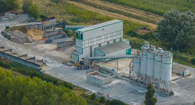 Loriol sur Drome Auvergne Rhone Alpes France 26 July 2026 Aerial view of an industrial concrete facility with silos conveyors and aggregate bays in an agricultural landscape.