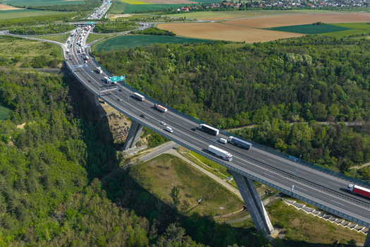 Aerial view of a highway bridge spanning a lush green valley with heavy traffic and trucks moving along the road in Prague Prague Czechia.