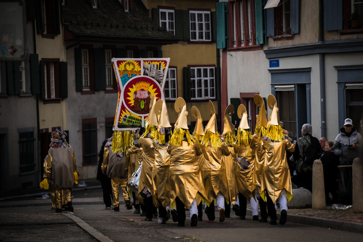 Basel Switzerland 10 March 2025 View of a parade of golden clad figures marching down a street near buildings their conical hats gleaming under the diffused light. Basel Switzerland 10 March 2025 View of a parade of golden clad figures marching down a street near buildings their conical hats gleaming under the diffused light.