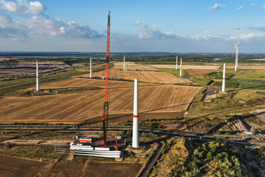 Aerial view of wind turbines under construction at the Schleenhain lignite open cast mine with a tall crane turbine blades on the ground and agricultural fields in Zwenkau Saxony Germany.