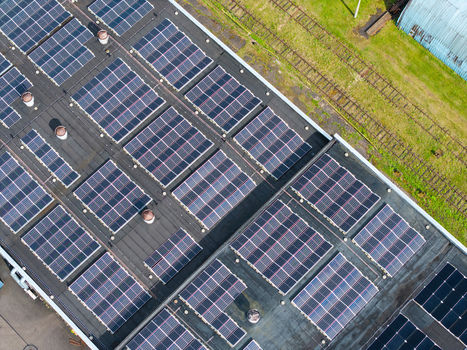 Aerial view of solar panels installed on a large industrial roof with adjacent railway tracks and green grass in Olaine Olaine Municipality Latvia. Aerial view of solar panels installed on a large industrial roof with adjacent railway tracks and green grass in Olaine Olaine Municipality Latvia.