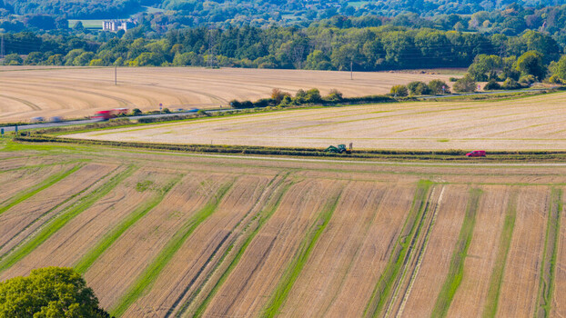Aerial view of the agricultural landscape at National Trust Pepperbox Hill featuring harvested fields a road with vehicles and green trees in Salisbury England United Kingdom. Aerial view of the agricultural landscape at National Trust Pepperbox Hill featuring harvested fields a road with vehicles and green trees in Salisbury England United Kingdom.