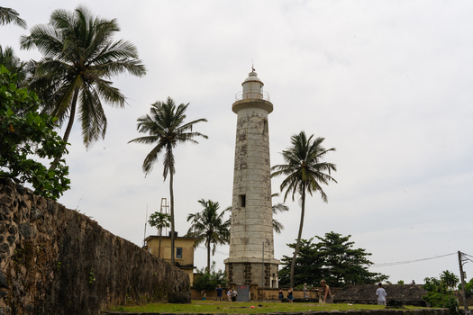 View of Galle Lighthouse surrounded by palm trees and historic stone walls in Galle Southern Province Sri Lanka.