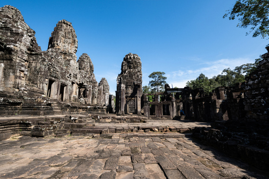 View of the ancient stone towers and intricate carvings of the Bayon Temple under a clear blue sky in Krong Siem Reap Siem Reap Province Cambodia. View of the ancient stone towers and intricate carvings of the Bayon Temple under a clear blue sky in Krong Siem Reap Siem Reap Province Cambodia.